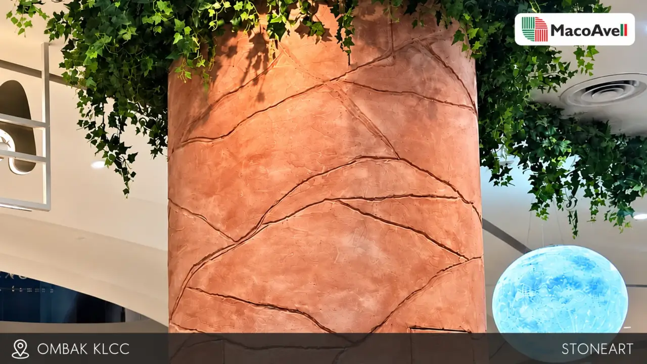 Terracotta-toned StoneArt column at Ombak KLCC with irregular stone-like lines, overhead greenery and a blue illuminated sphere.
