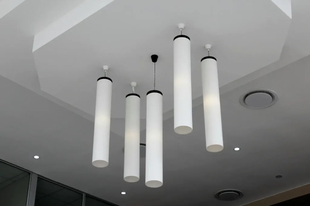 Minimalist modern interior with cylindrical hanging lights on a white ceiling.