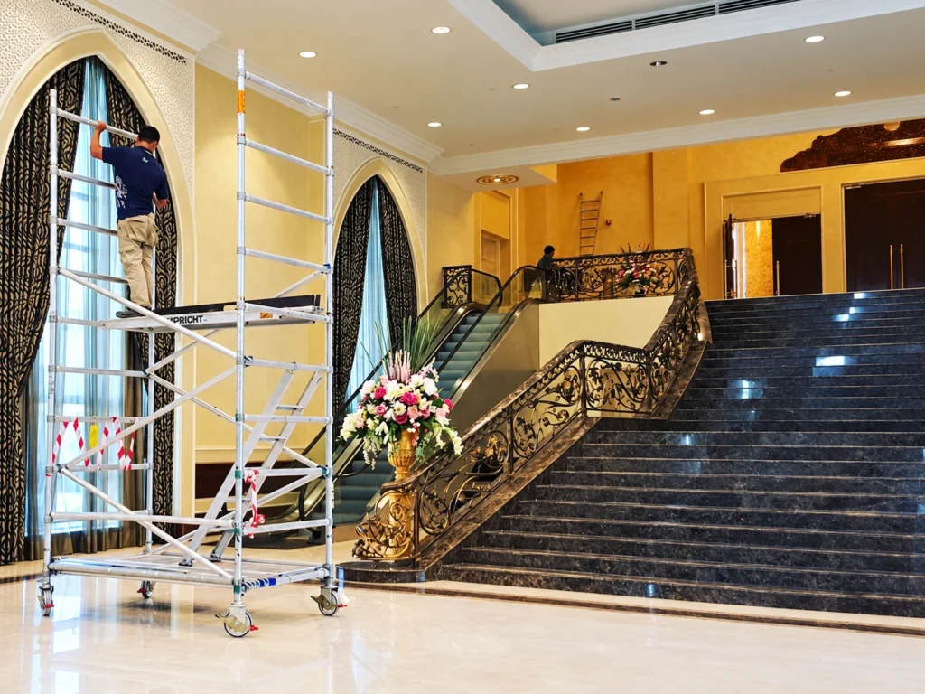 Warm cream and gold-toned textured walls beside arched windows and a dark staircase at Istana Negara.