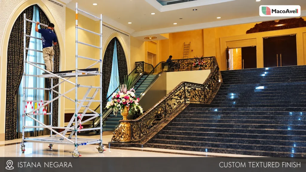 Istana Negara foyer with warm cream and gold-toned textured walls, staircase and scaffolding, with MacoAvell branding and project labels.