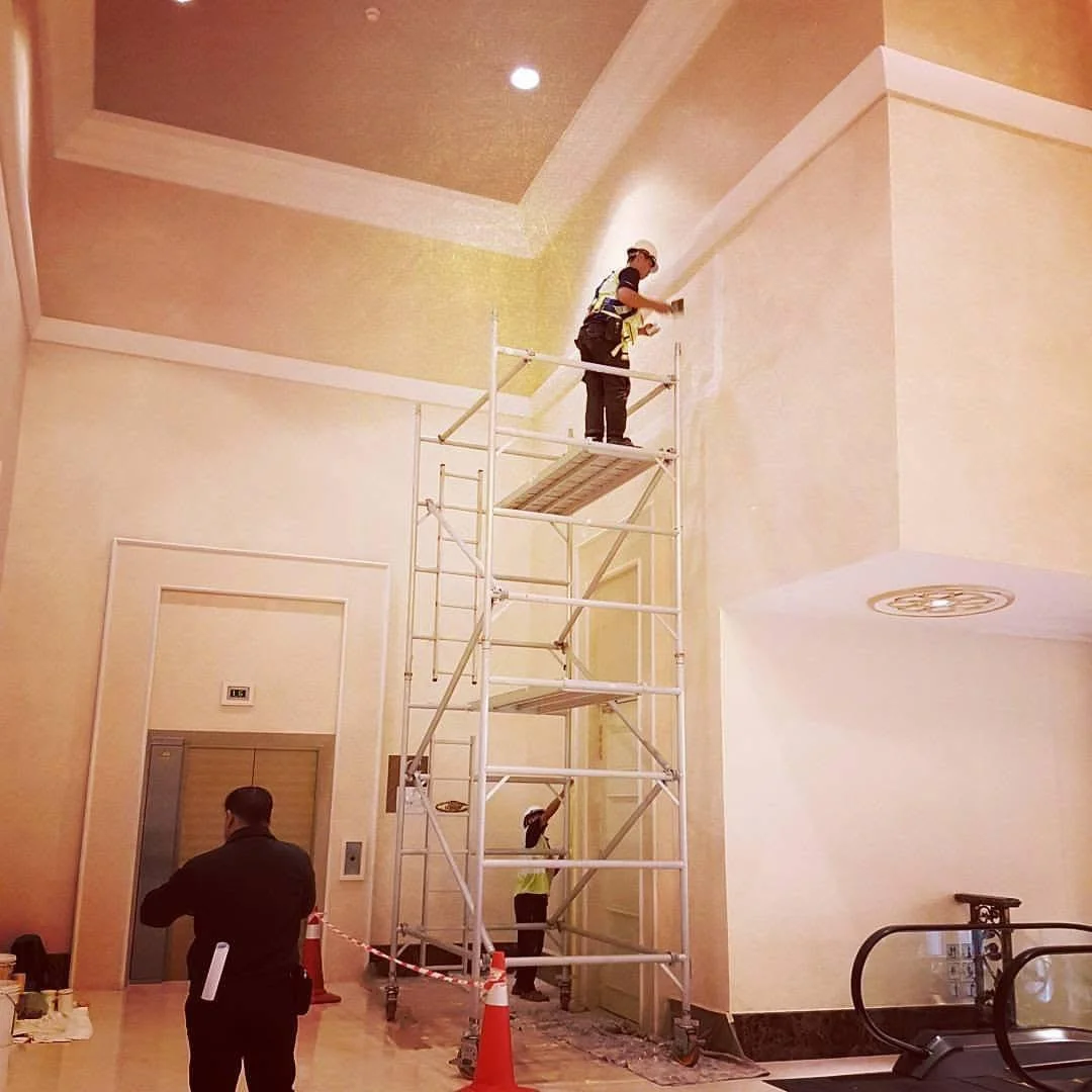 Applicator on scaffolding working on a high interior wall at Istana Negara.