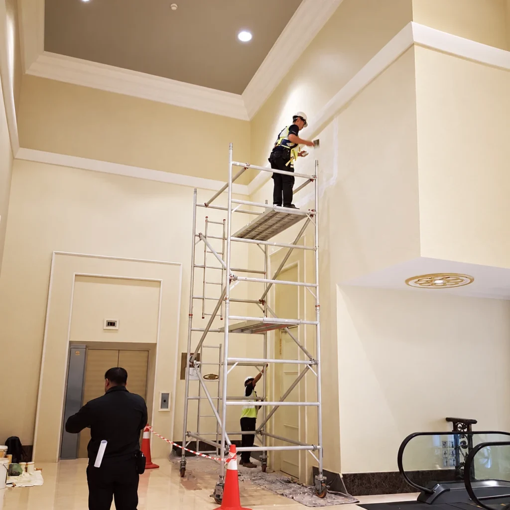 Workers applying a finish from scaffolding on the high interior walls at Istana Negara.