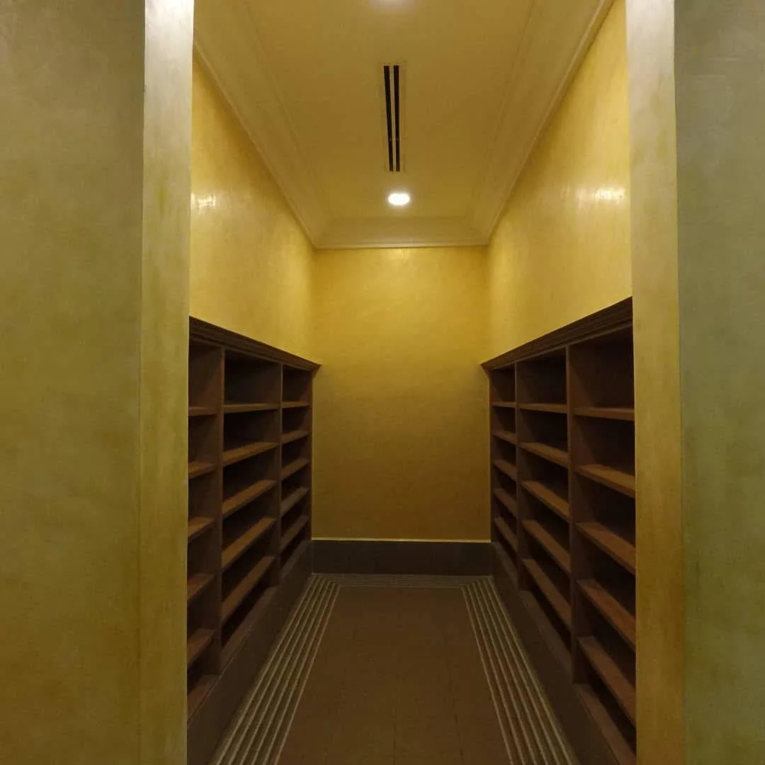 Warm yellow textured walls above dark timber shelving at Istana Negara.