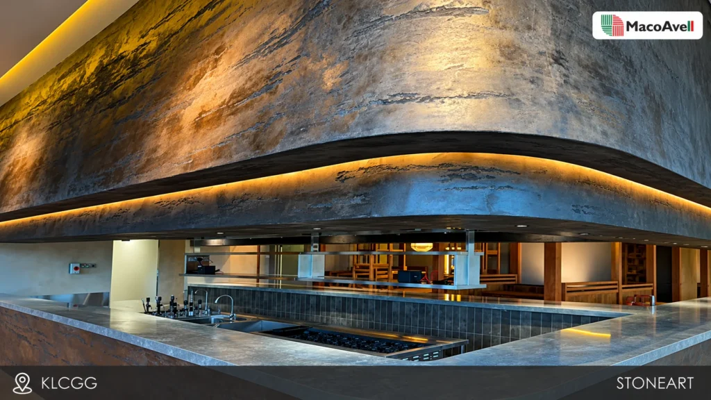 StoneArt curved overhead feature at KLCGG with layered grey texture and warm linear lighting above an open kitchen counter.