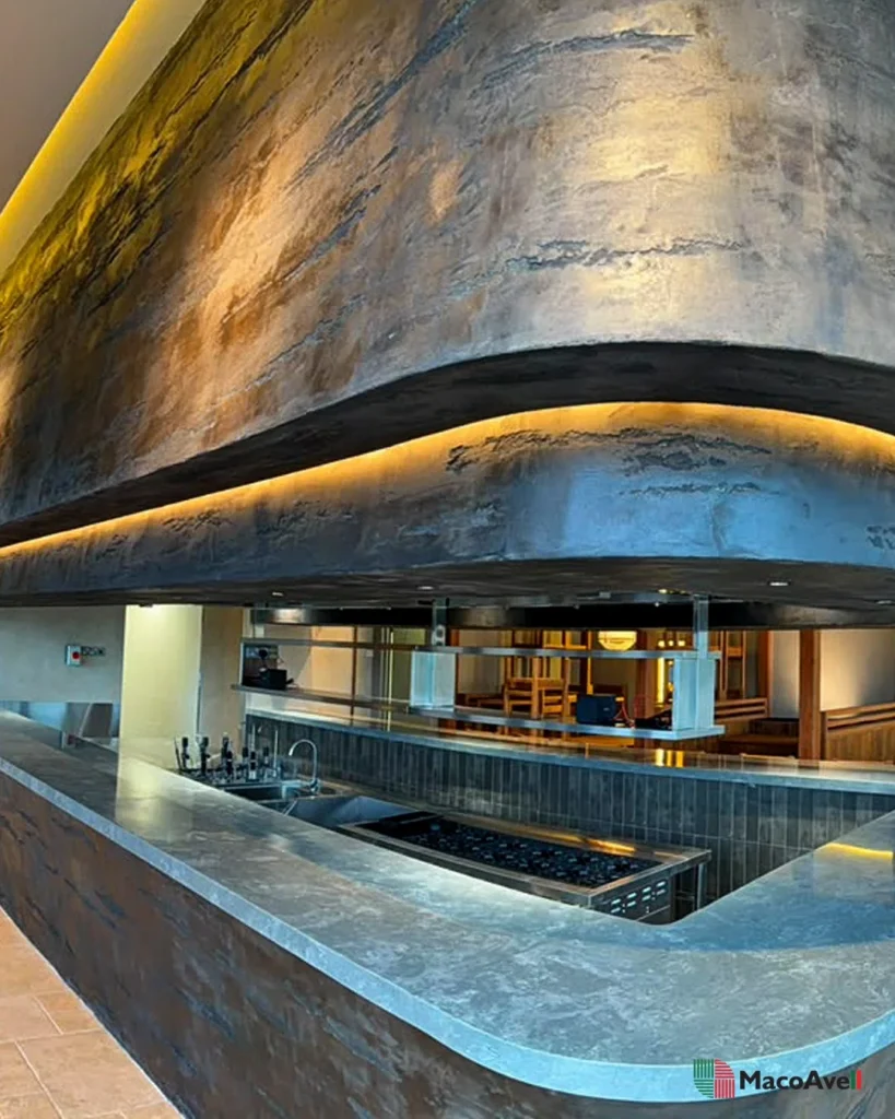 Curved StoneArt feature and recessed warm light band above the open kitchen at KLCGG.
