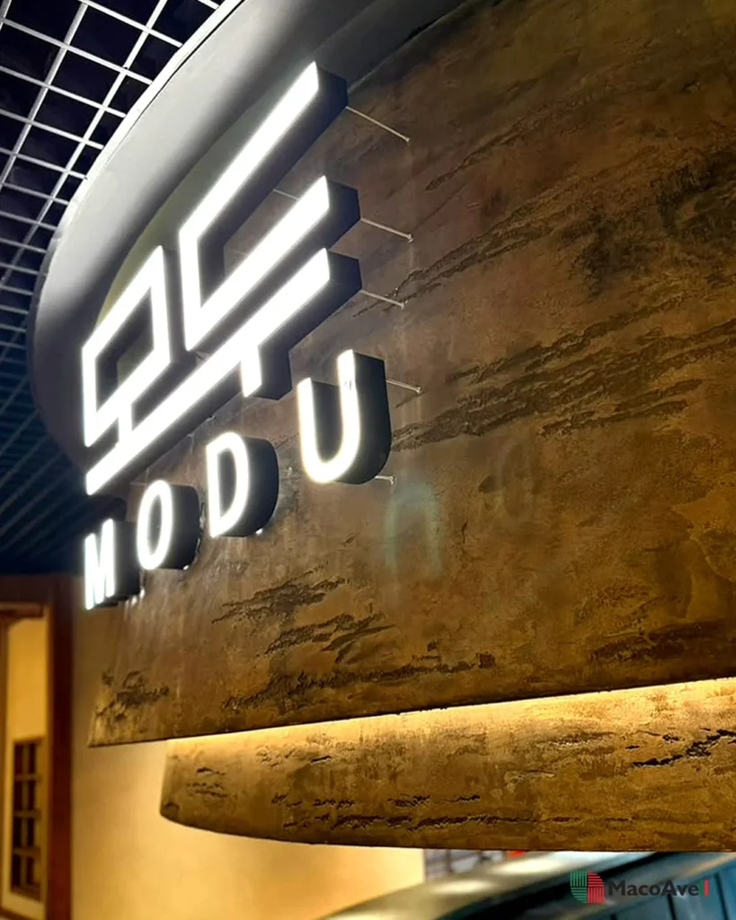 Illuminated MODU signage against the layered StoneArt surface at KLCGG.