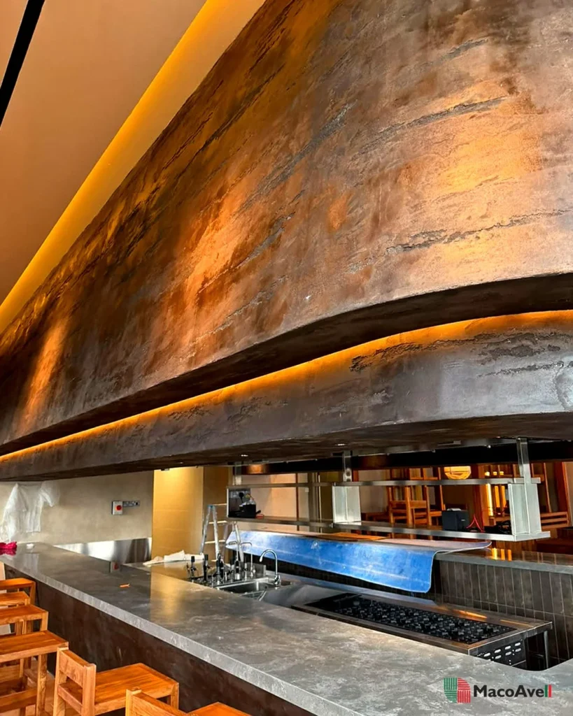StoneArt layered texture at KLCGG under warm lighting above an open kitchen counter with timber seating.