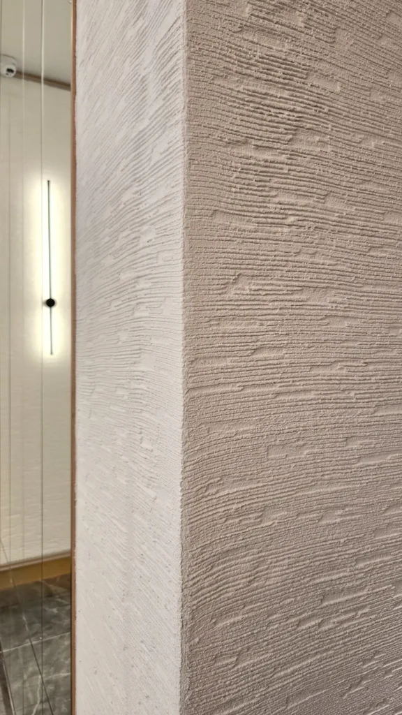 Vellcco Custom horizontal texture wrapping around a wall corner beside a mirror.