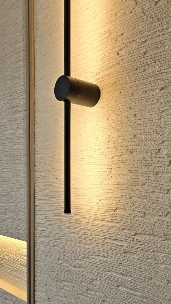 Black cylindrical wall light casting a warm glow over the horizontal Vellcco Custom texture.