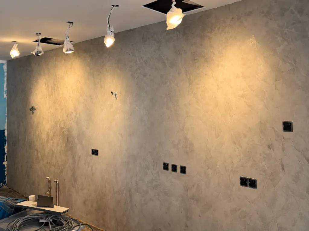 Vellplas MA02 wall in Kuala Lumpur, showing soft grey texture under warm pools of light.