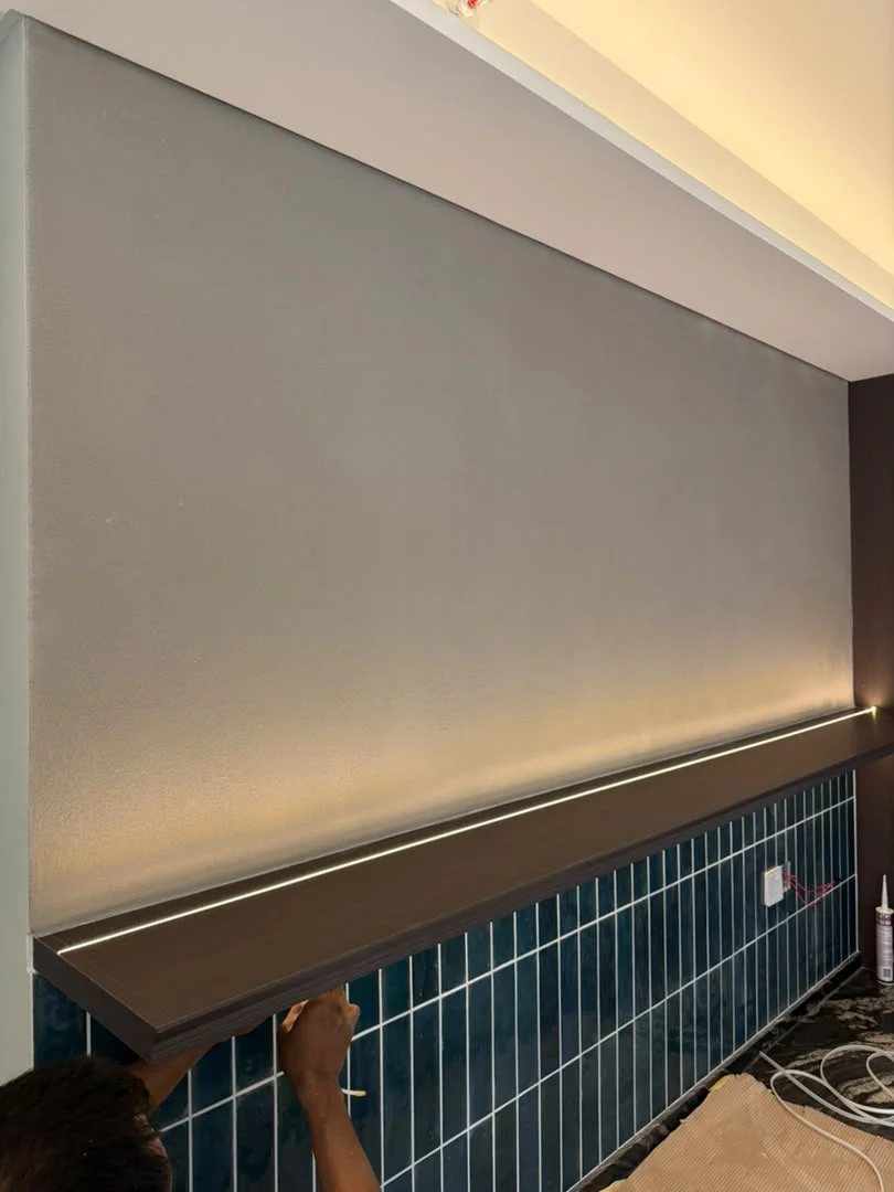 Vellcco MA01 pitted-effect feature wall above a dark ledge and blue vertical tiles during interior works.