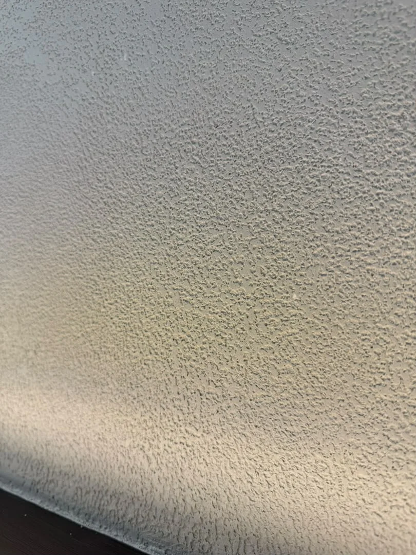 Close-up of the irregular pitted texture in Vellcco MA01, with warm light along the lower edge.